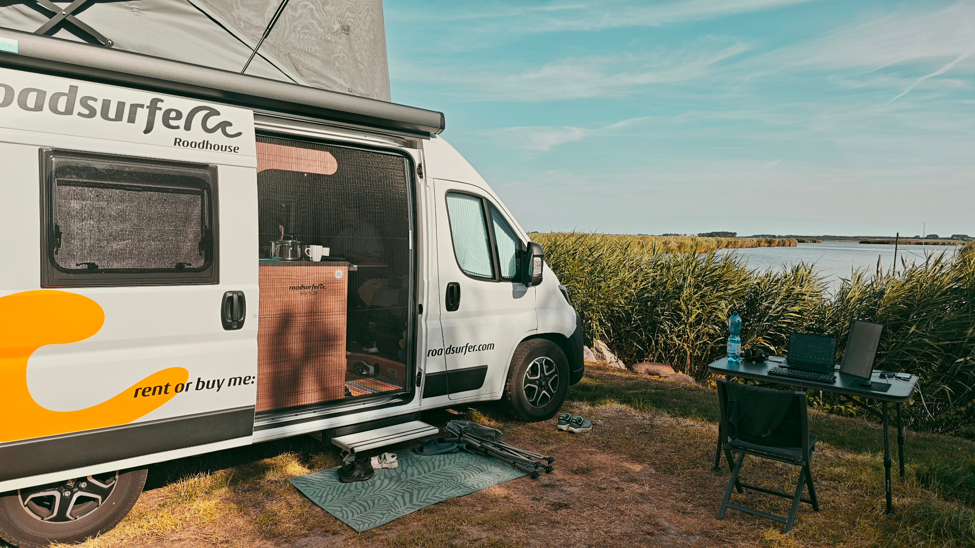 Unser Roadsurfer-Camper am Wasser mit Laptop-Arbeitsplatz auf dem Klapptisch